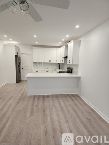 A kitchen with white cabinets and a wooden floor.