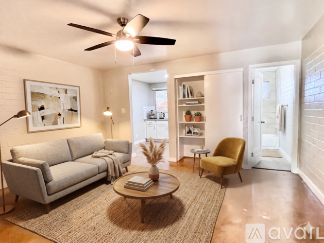 A living room with a grey sofa, a yellow chair, a coffee table, and a ceiling fan.