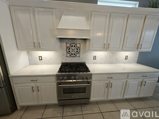 A kitchen with white cabinets and a stove top oven.