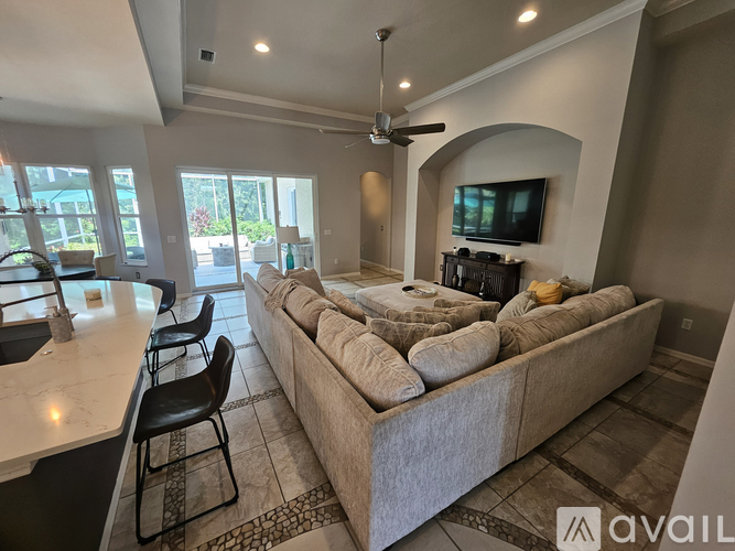 A living room with a large couch and a television on the wall.