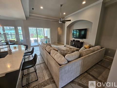 A living room with a large couch and a television on the wall.