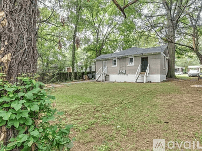 A small house is surrounded by trees and grass.