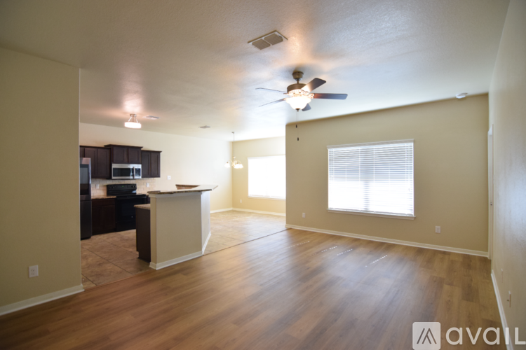 A spacious living room with a kitchen area in the background.