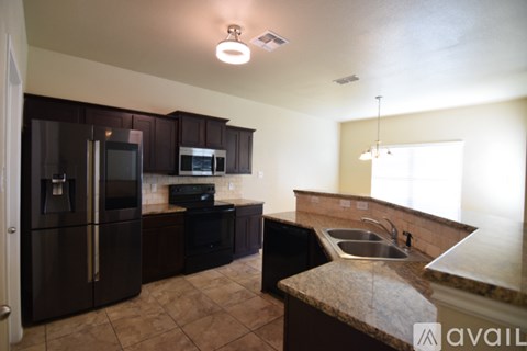 A kitchen with brown cabinets and a black refrigerator.