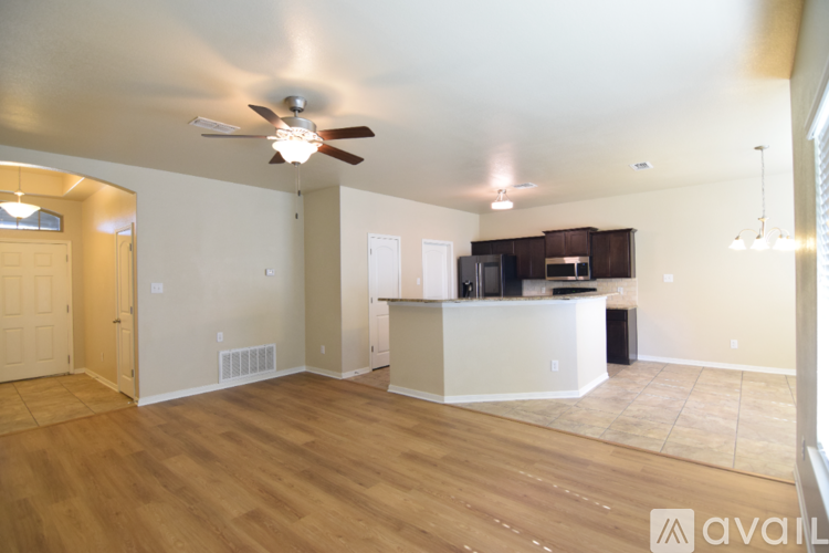 A spacious living room with a ceiling fan and hardwood floors.