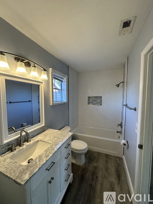 A bathroom with a sink, toilet, and mirror.