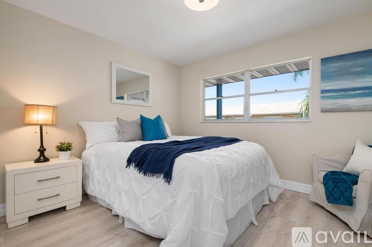 A bedroom with a white bed and a blue blanket.