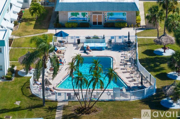 A pool surrounded by palm trees and a white fence.