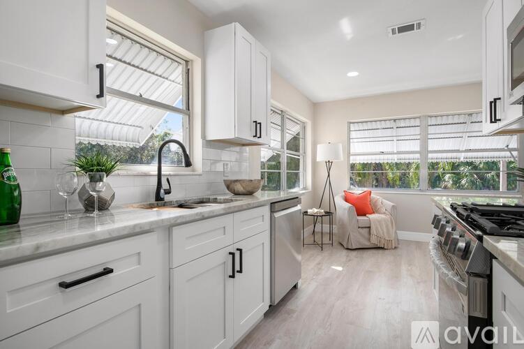 A kitchen with white cabinets and a marble countertop.