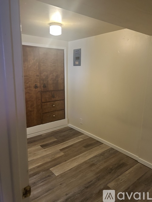 A hallway with a wooden floor and a white wall with a sign on it.