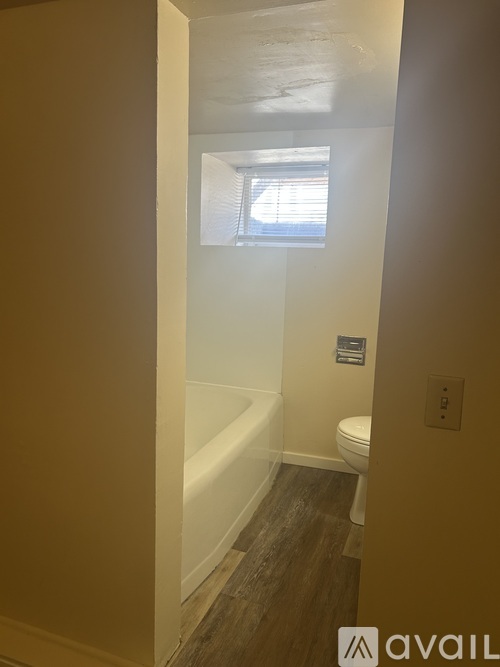 A bathroom with a toilet, tub, and window.