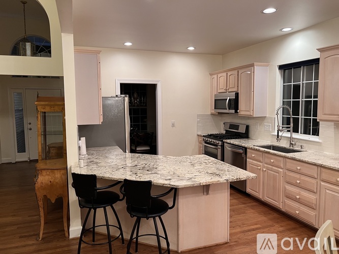 A kitchen with a marble countertop and black barstools.