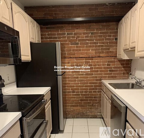A kitchen with a black refrigerator and white cabinets.