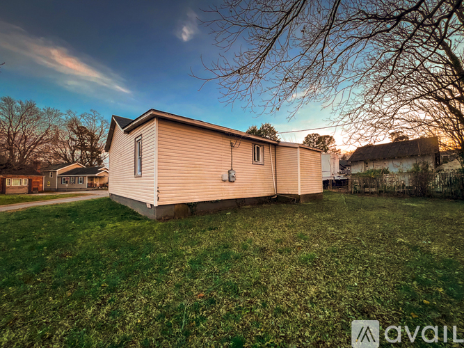 A mobile home sits in a grassy field with trees in the background.