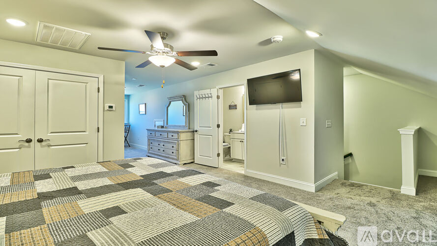 A spacious room with a ceiling fan and a television mounted on the wall.