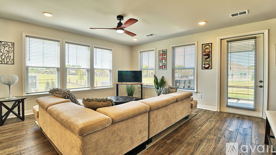 A living room with a couch, a television, and a ceiling fan.
