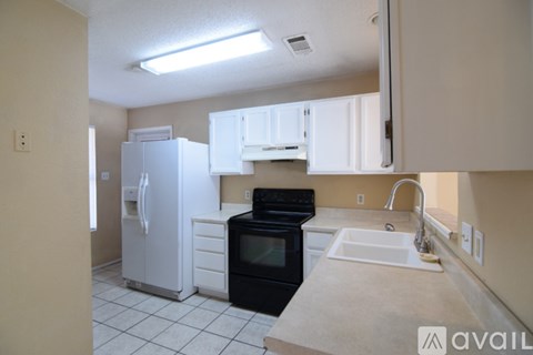 A kitchen with white cabinets and black appliances.