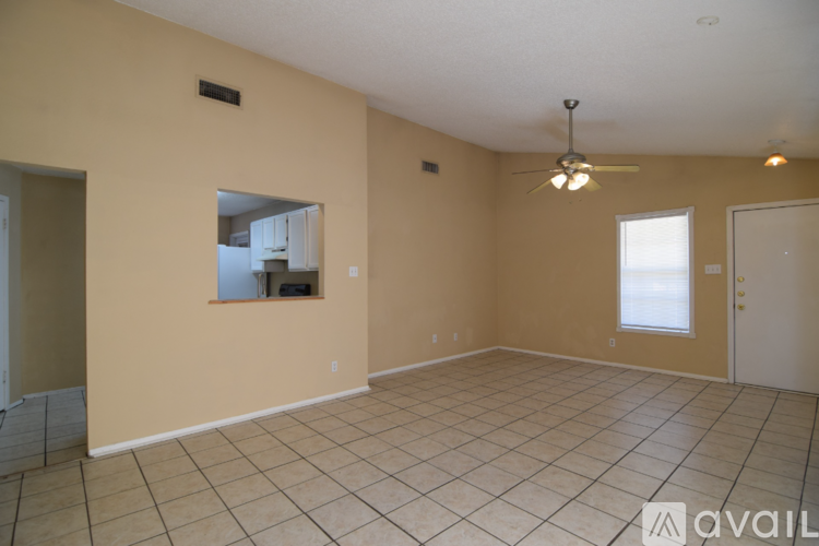 A spacious room with beige walls and a ceiling fan.