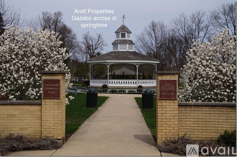 A gazebo is surrounded by flowering trees in the spring.