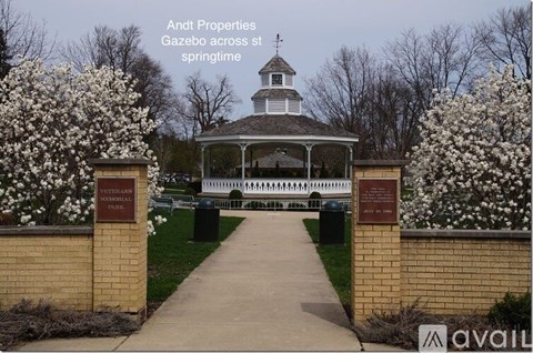 A gazebo is surrounded by flowering trees in the spring.