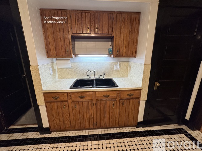 A kitchen with wooden cabinets and a black and white tiled floor.