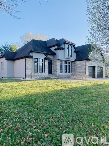A large house with a black roof and a grey brick exterior.
