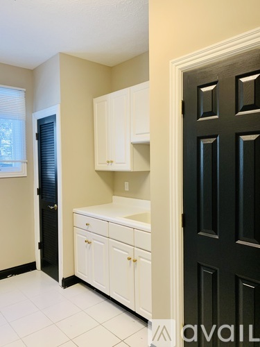 A kitchen with white cabinets and a black door.
