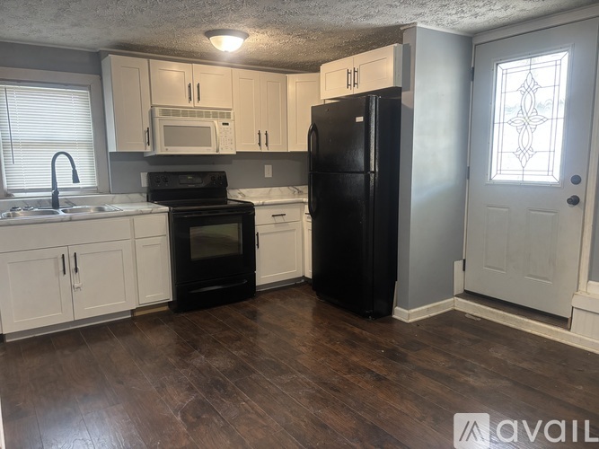 A kitchen with black appliances and white cabinets.