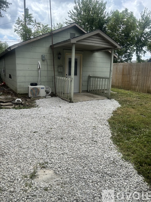A small house with a gravel driveway in front.