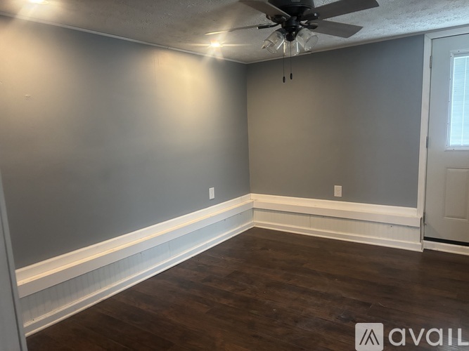 A room with a ceiling fan and wooden flooring.