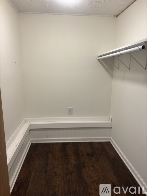 A small room with a shelf and a wooden floor.
