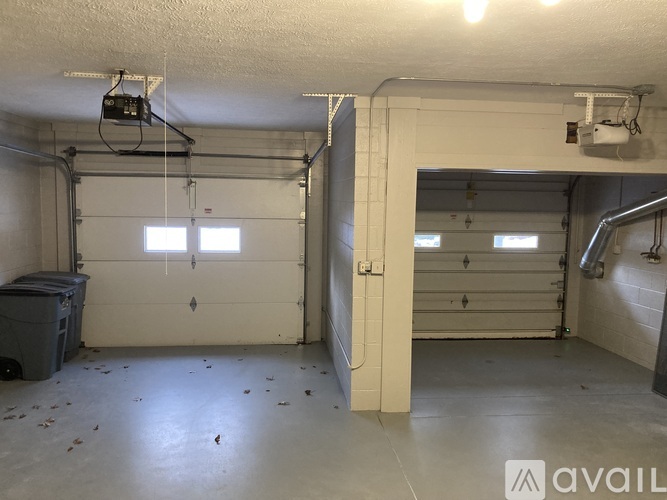 A spacious garage with two doors and a window, and a trash bin on the left.