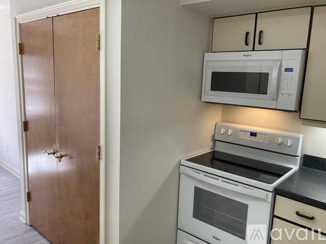A kitchen with a white microwave and oven, a wooden door, and a black countertop.