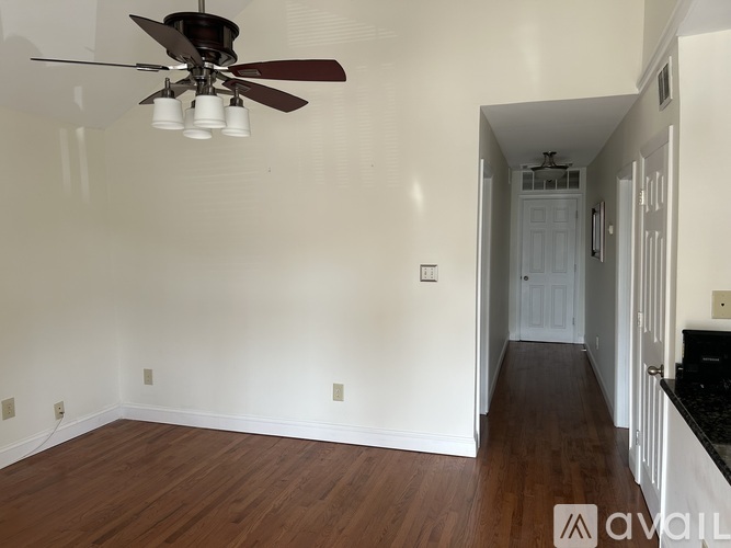 A room with a ceiling fan and wooden floors.