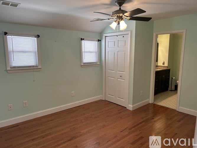 A room with a ceiling fan and wooden flooring.