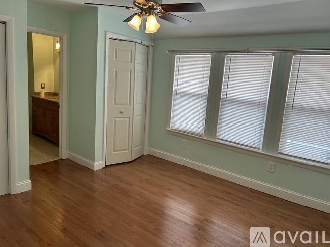 A room with a ceiling fan and a window with blinds.