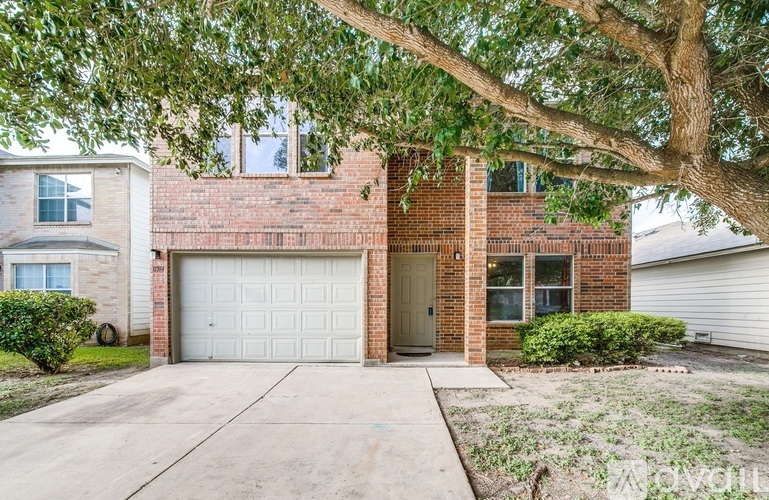 A house with a white garage door and a tree in front.