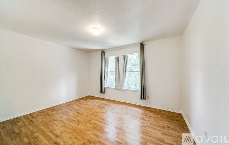 A room with wooden flooring and a window with curtains.