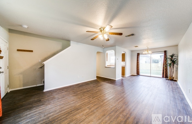 A spacious room with wooden flooring and a ceiling fan.