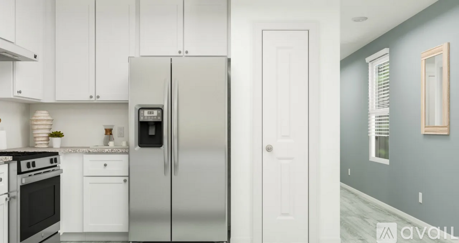 A kitchen with white cabinets and a stainless steel refrigerator.