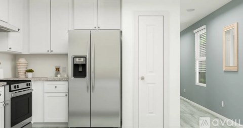 A kitchen with white cabinets and a stainless steel refrigerator.