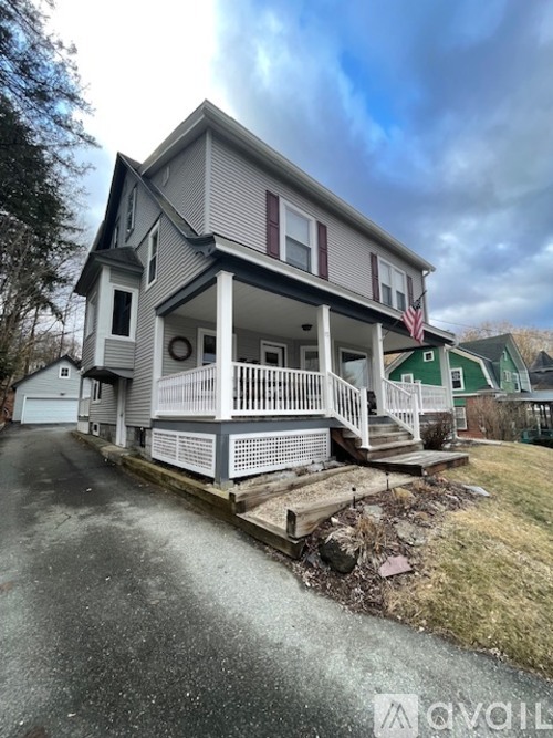 A two-story house with a grey exterior and a white porch.