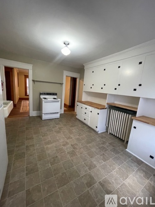 A kitchen with white cabinets and a tile floor.