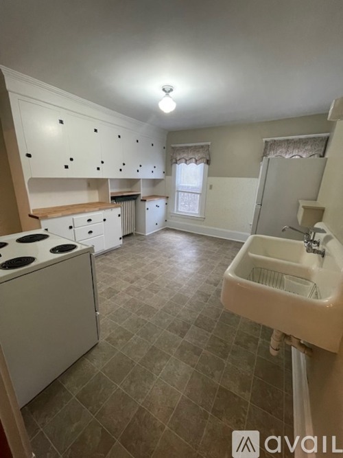 A kitchen with a stove, sink, and cabinets.