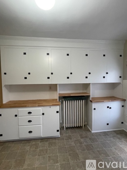 A kitchen with white cabinets and a radiator.
