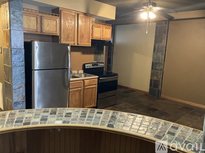 A kitchen with a stainless steel refrigerator and wooden cabinets.