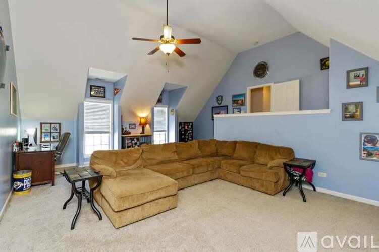 A living room with a tan couch and a ceiling fan.