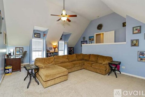 A living room with a tan couch and a ceiling fan.