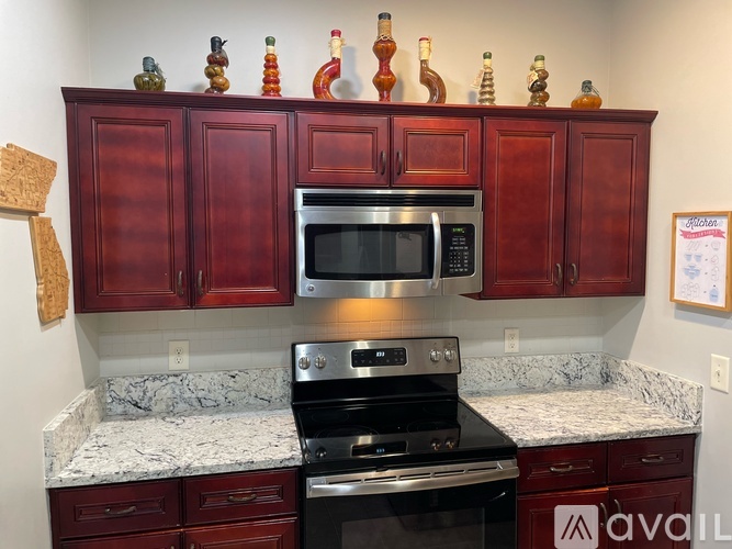 A kitchen with red cabinets and a stove top oven.