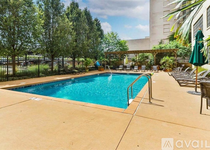 A swimming pool surrounded by trees and chairs.